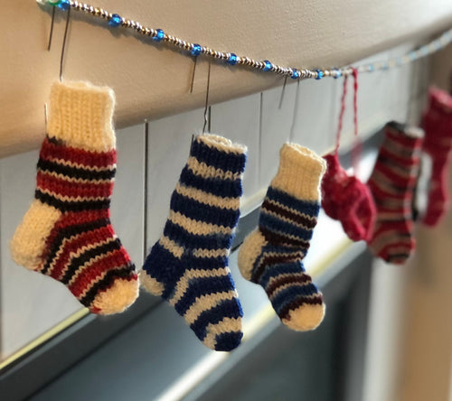 Image of mini stockings hanging by the fire with care, in hopes that St. Nicholas would fill them with a candy!