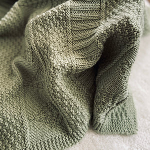 A photo of the corner of a cozy blanket. The blanket pattern is called Islander and is from the book, Newfoundland Knits for Little Ones by Katie Noseworthy.