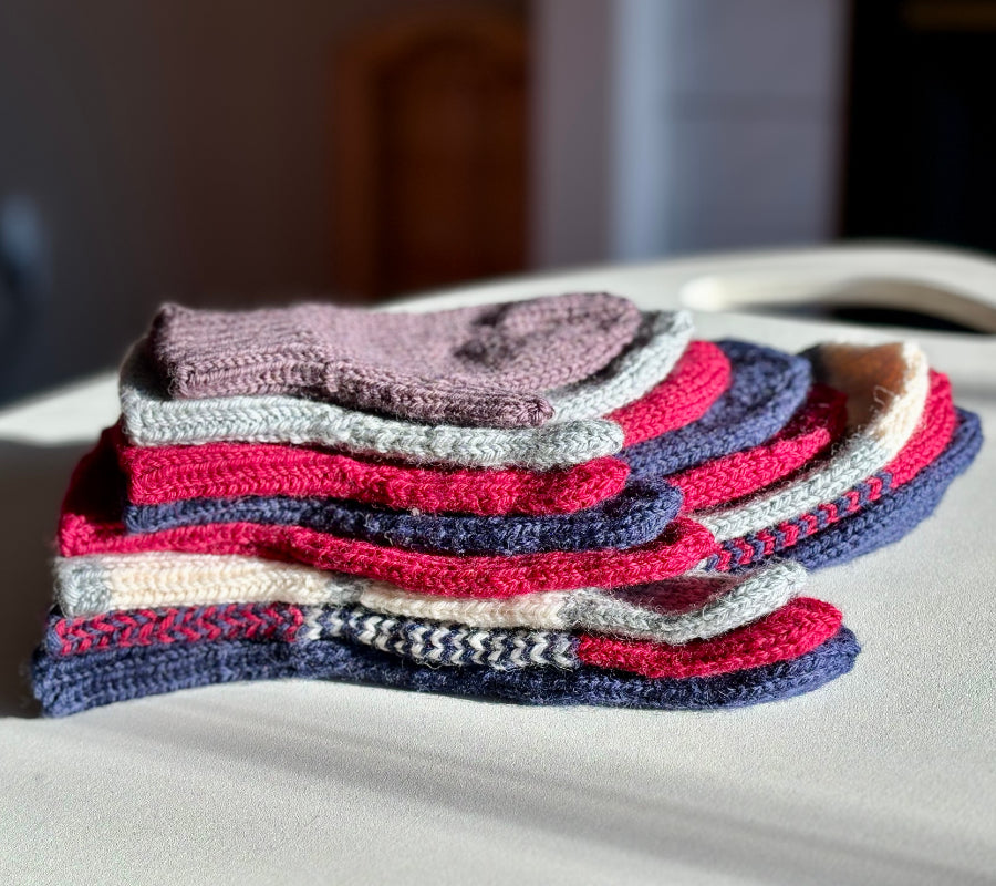 A stack of mittens, one in each size included in the pattern.