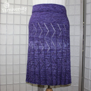 An image of a knitted skirt with lacy zig zags running down the pleats. Knitted in Ancient Arts Merino + Silk.