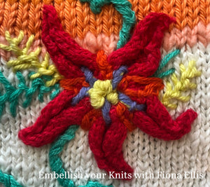 Image of a beautiful flower element added to a knit piece. Embroidered details provide visual elements to make the flower more dimensional and to add stems, leaves and colourful sprays to the centrepiece.