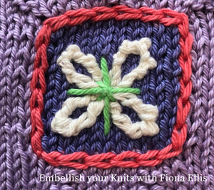 Image of an intarsia block, come to life with a border and flower element embroidered on "after knit". 