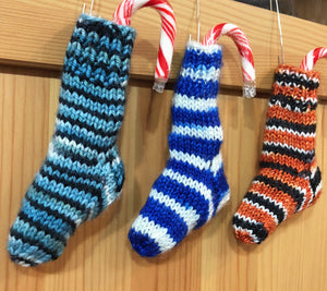 Image of three mini Christmas stockings, each holding a candy cane.